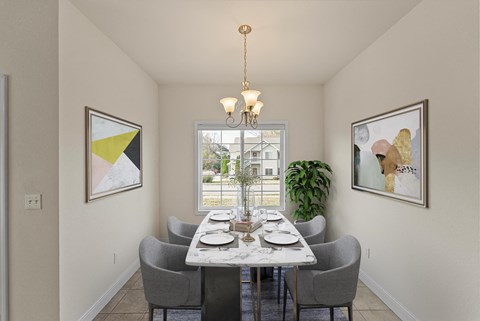 A dining room with a table set for two and a view of a building outside the window.