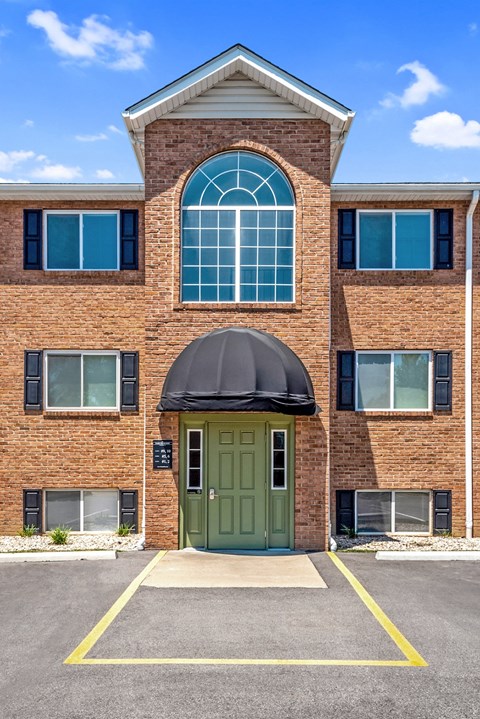 the front of a brick building with a green door and an awning