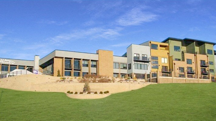 a view of the exterior of an apartment building with a green lawn