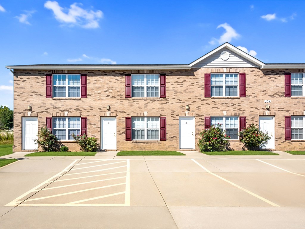 a large brick building with red shuttered windows and a parking lot