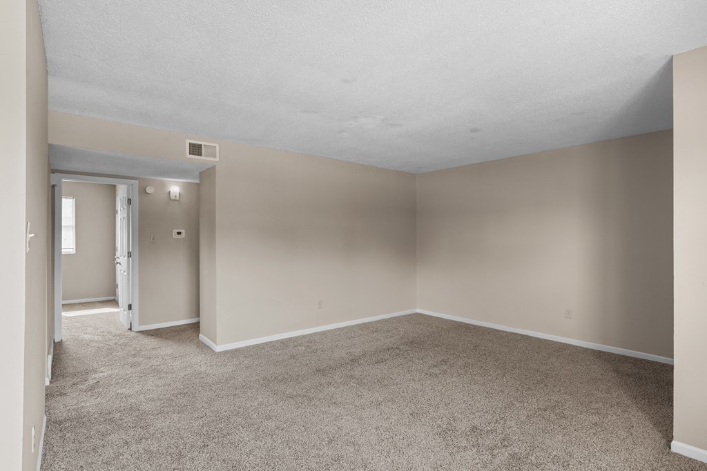 an empty living room with beige carpet and white walls