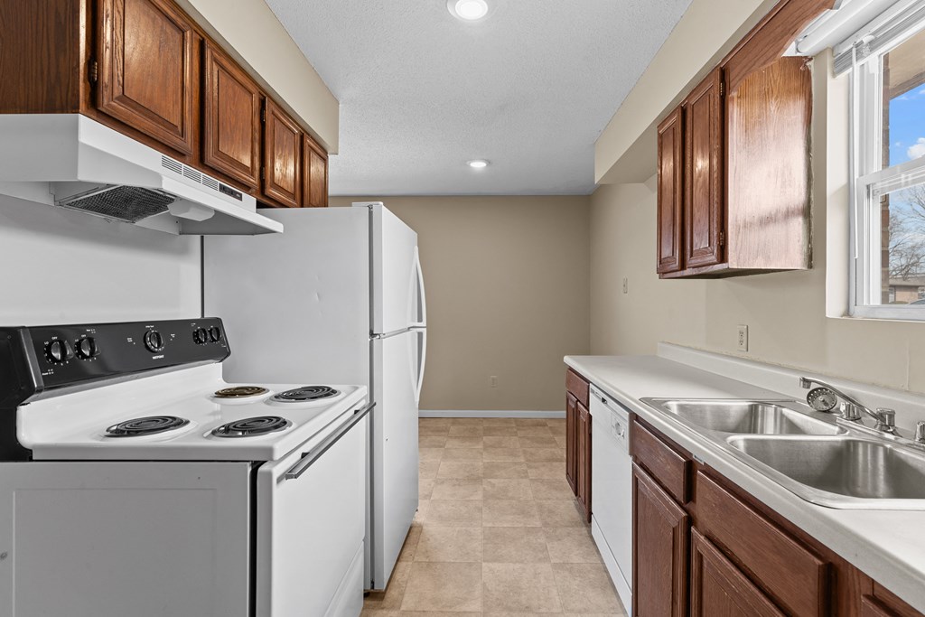 an empty kitchen with white appliances and wooden cabinets