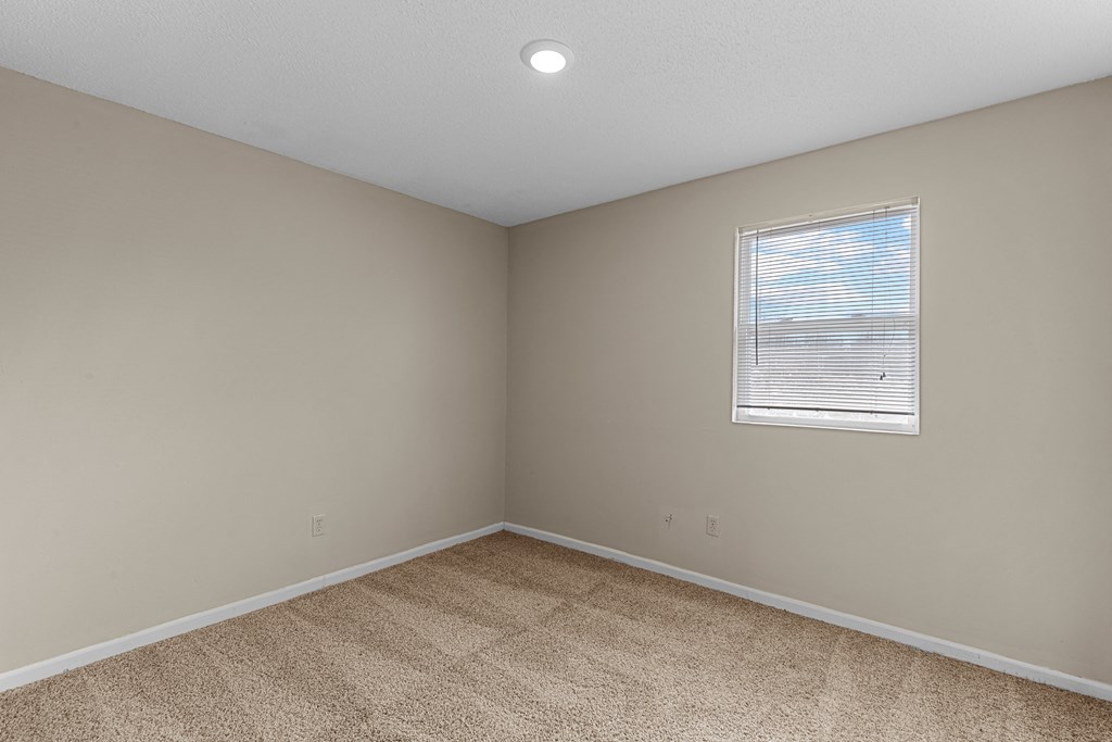 an empty room with beige walls and a window