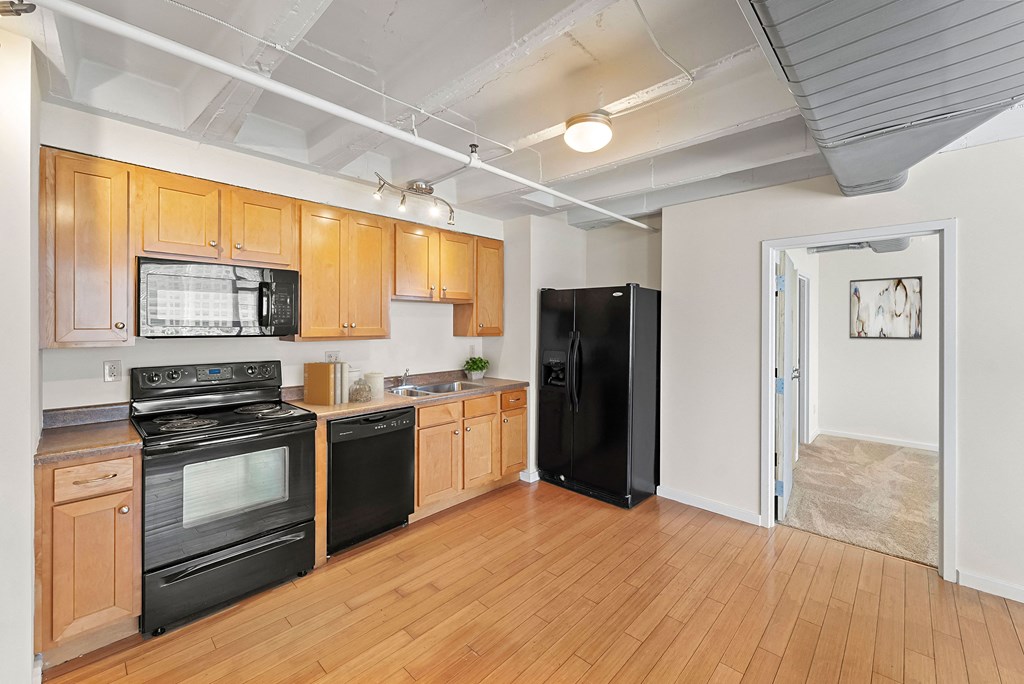 a kitchen with black appliances and wood flooring and a black refrigerator