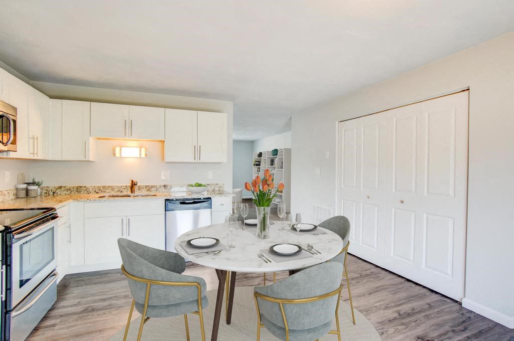 a dining area with a table and chairs and a kitchen in the background