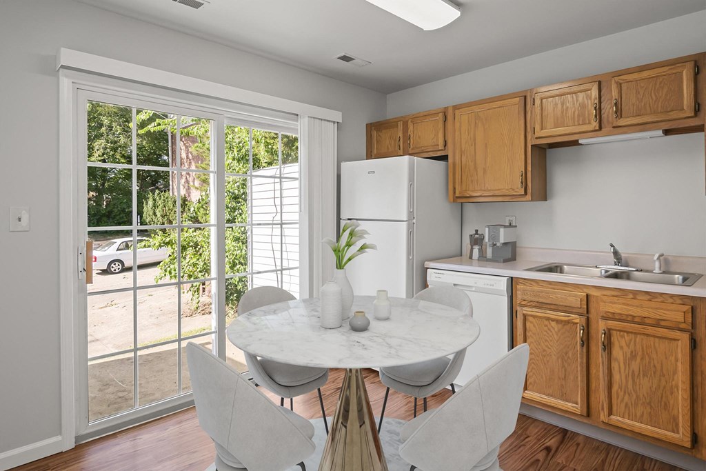 a kitchen with wood cabinets and a white marble table with four white chairs