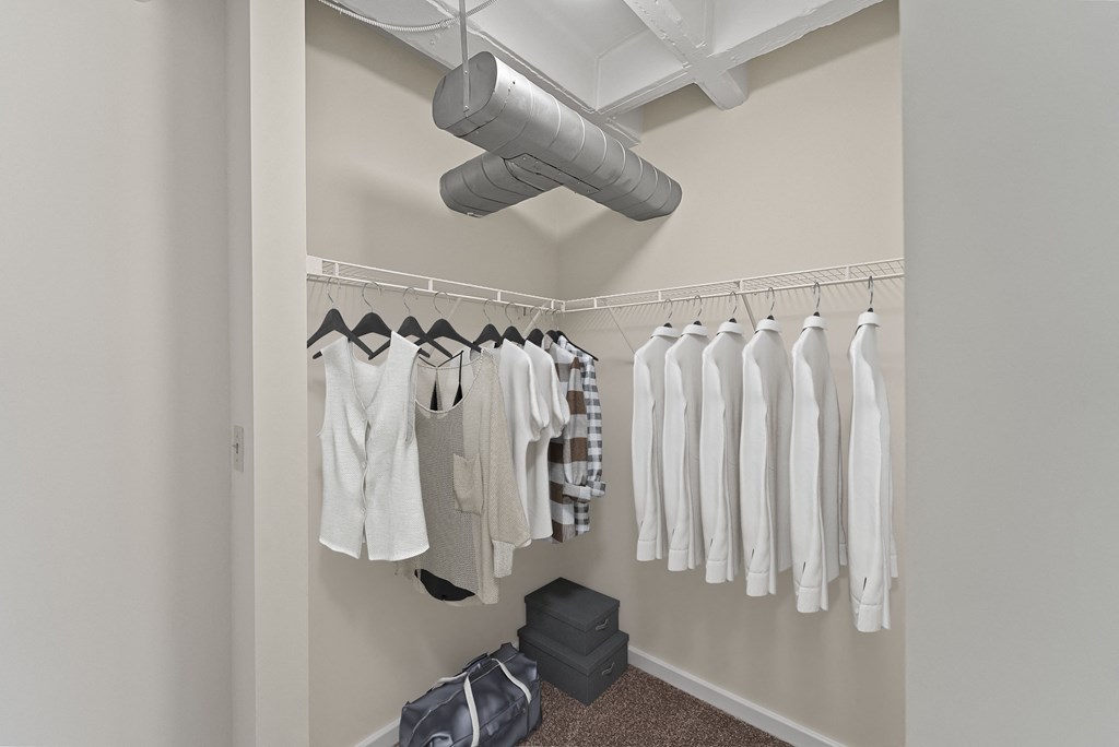 a closet with clothes hanging on a rack and a ceiling fan