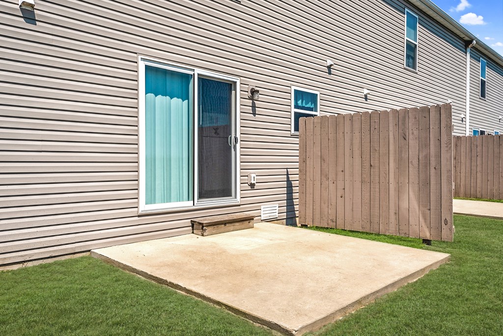 a patio in front of a house with a wooden fence