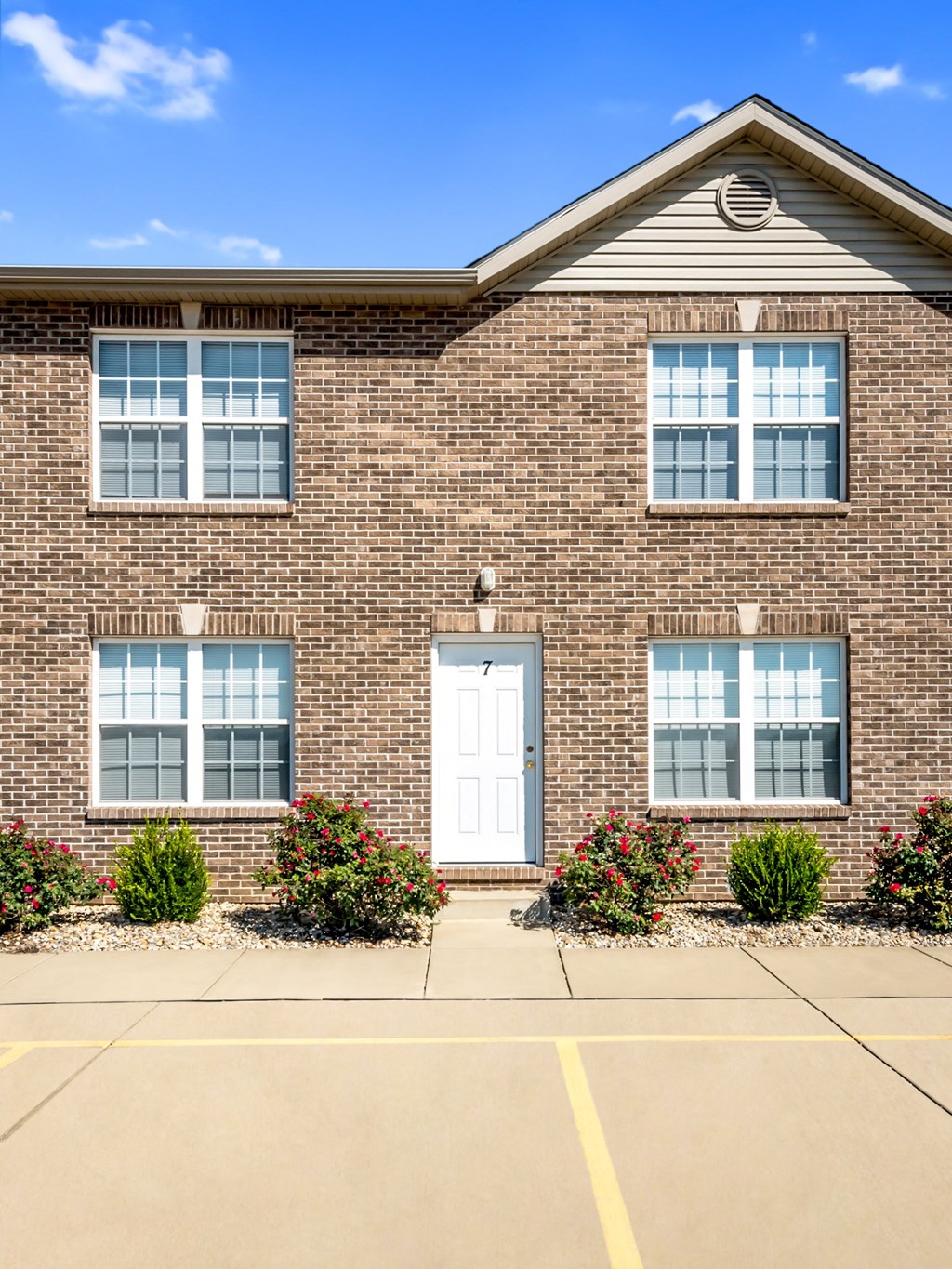 the front of a brick building with a white door and windows