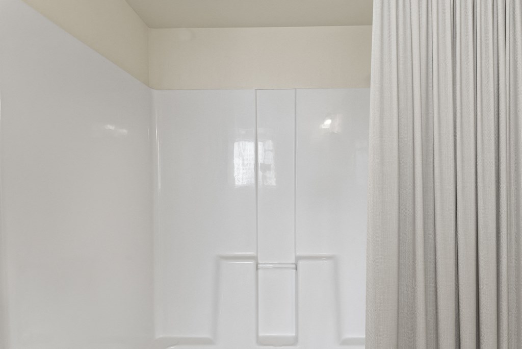 a bathroom with white walls and a shower curtain