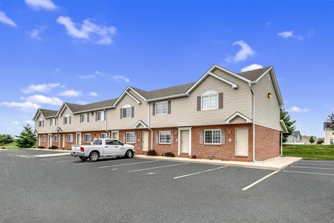 the view of a large apartment building with a truck parked in a parking lot