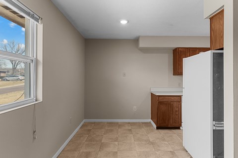 A kitchen area with a white refrigerator and wooden cabinets.