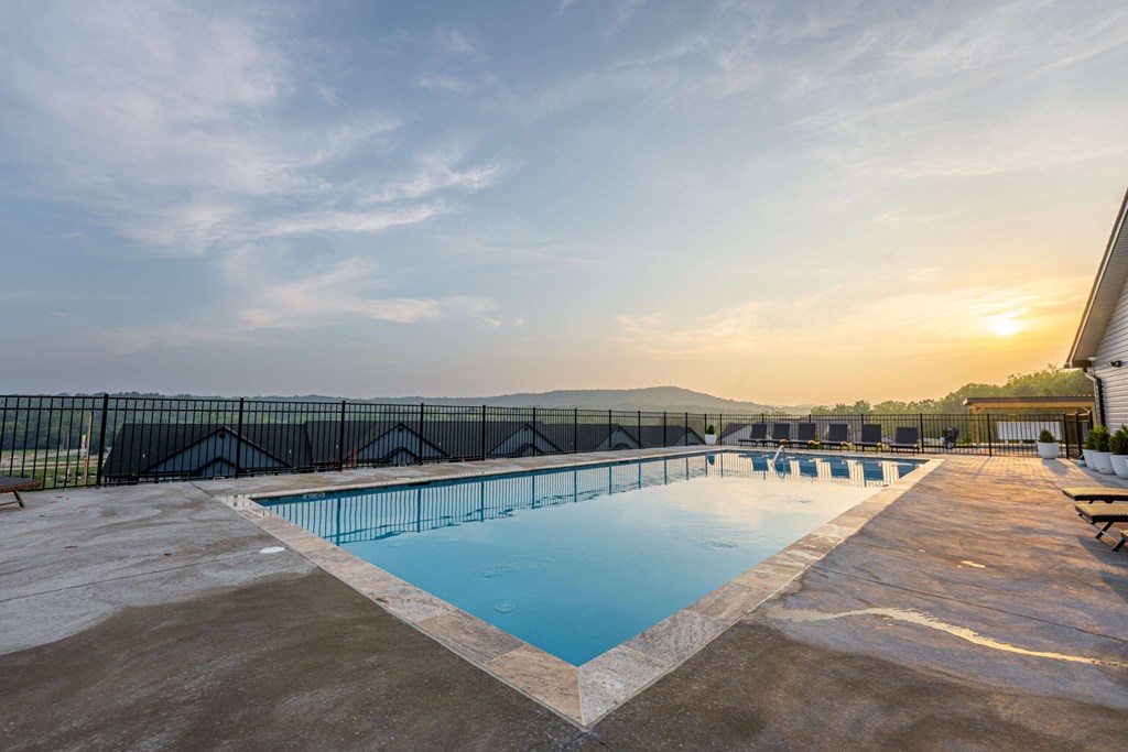 A large outdoor swimming pool with a sunset in the background.