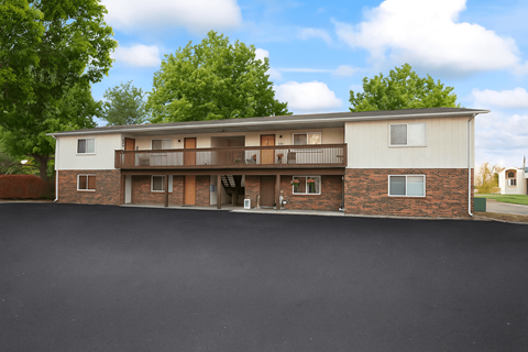 A two-story apartment building with a parking lot in front.