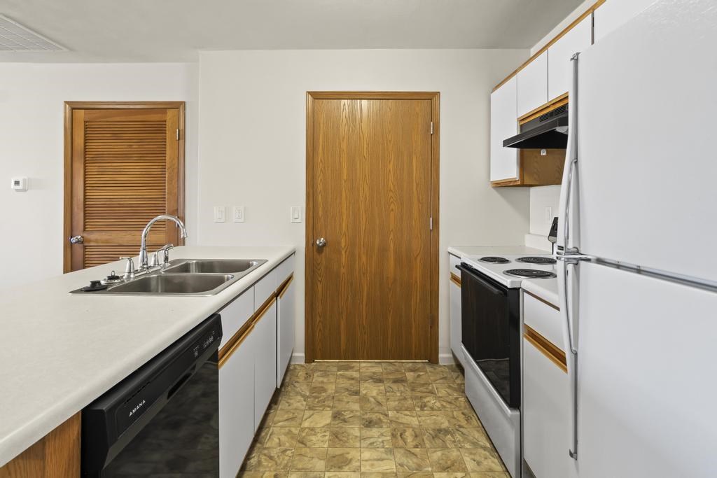 A kitchen with a sink, stove, and refrigerator.