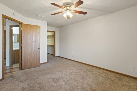 A room with a ceiling fan and carpeted floor.