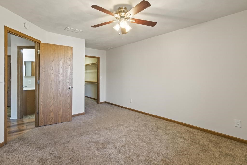 A room with a ceiling fan and carpeted floor.