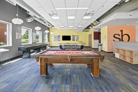 A room with a pool table and a bar area.