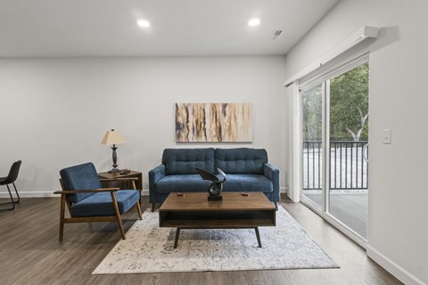 A living room with a blue couch and a wooden table.