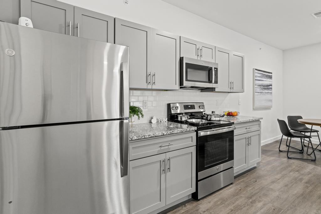 A modern kitchen with a refrigerator, microwave, oven, and a dining table.