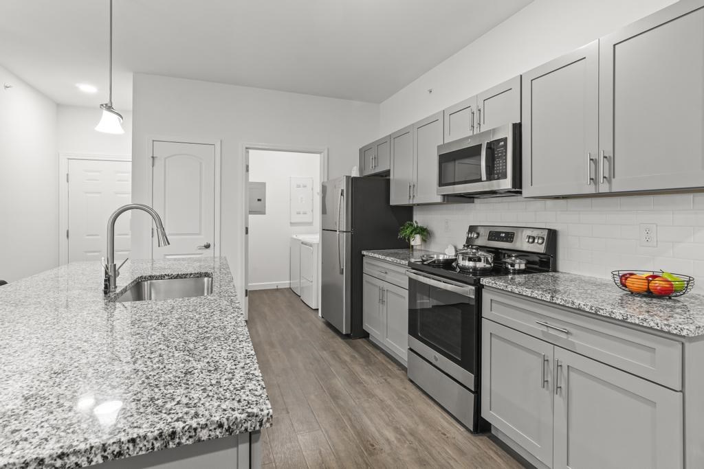 A kitchen with a granite countertop and stainless steel appliances.