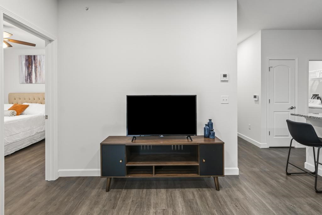 A black television is on a wooden stand in a white room.