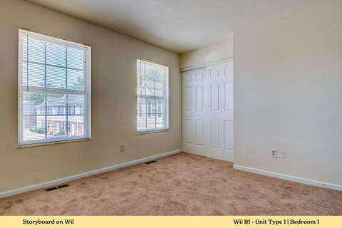 A bedroom with a carpeted floor and a window.