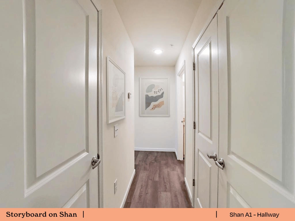 a hallway with white doors and white walls and wood floors