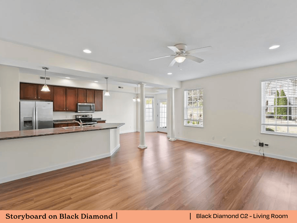 an open kitchen and living room with wood flooring and a ceiling fan