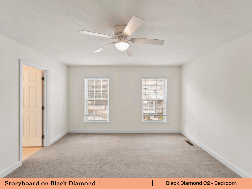an empty living room with a ceiling fan and two windows