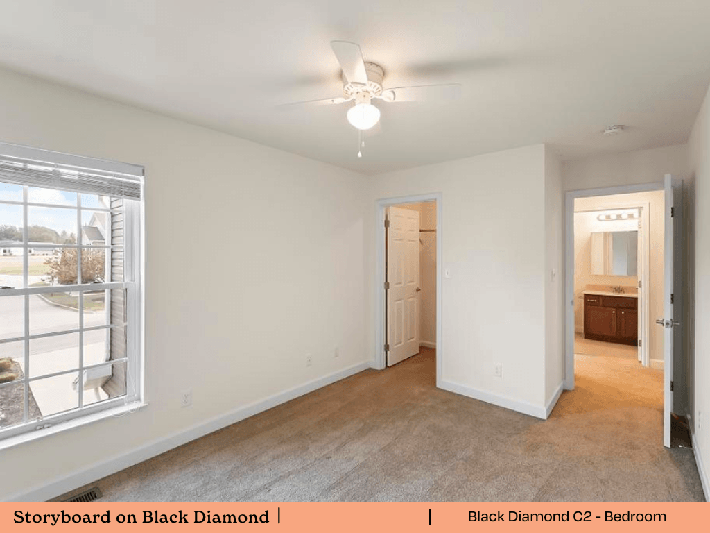an empty living room with a large window and a ceiling fan
