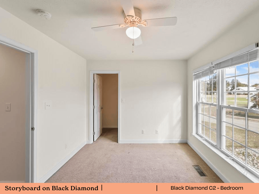 an empty living room with a ceiling fan and a large window