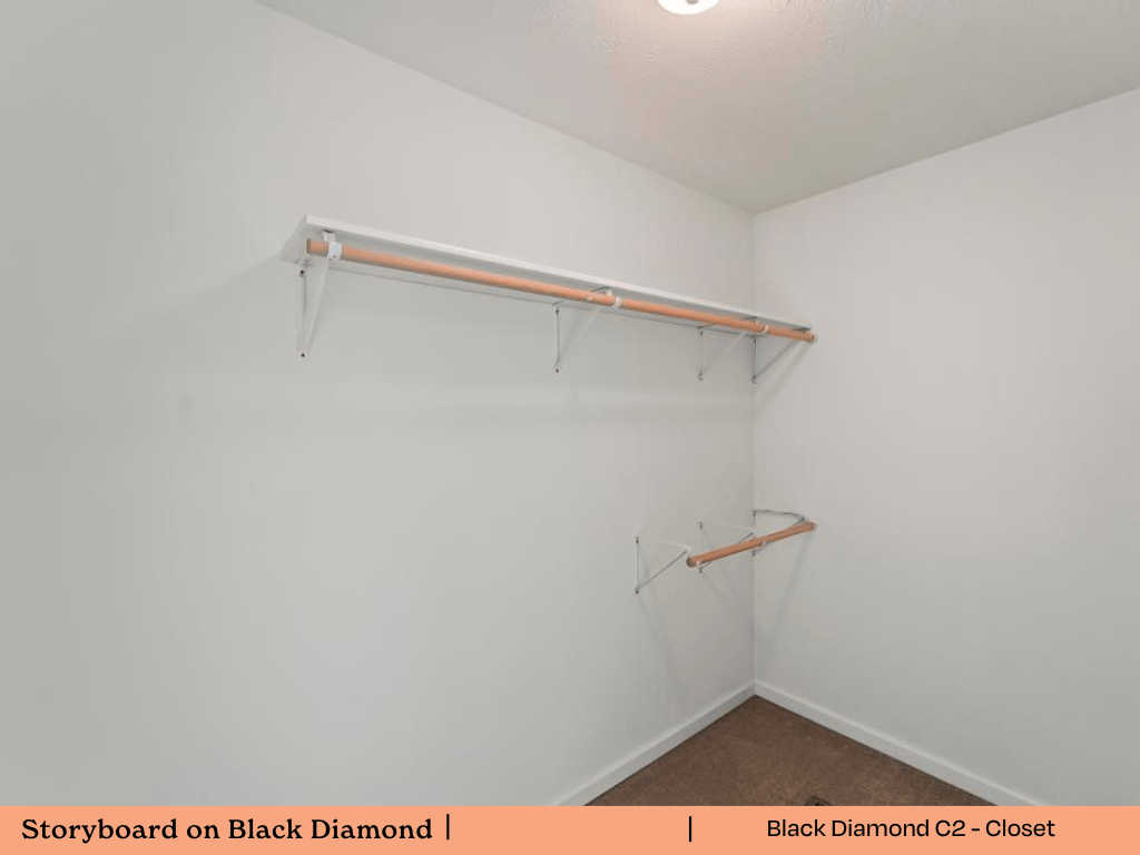 a walk in closet with a white wall and a hanging rack on the wall