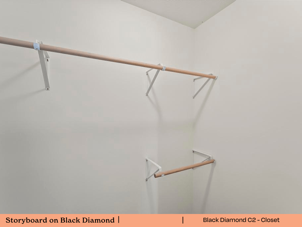 a walk in closet with a white wall and a rack on the wall