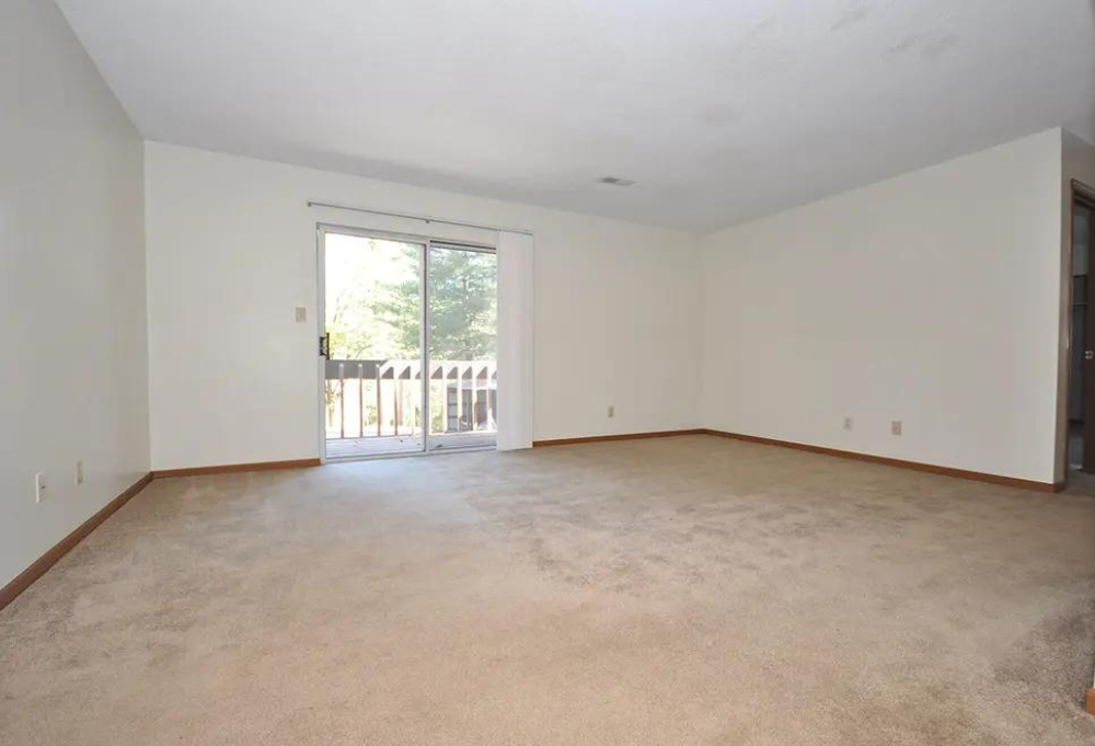 an empty living room with a door to a balcony
