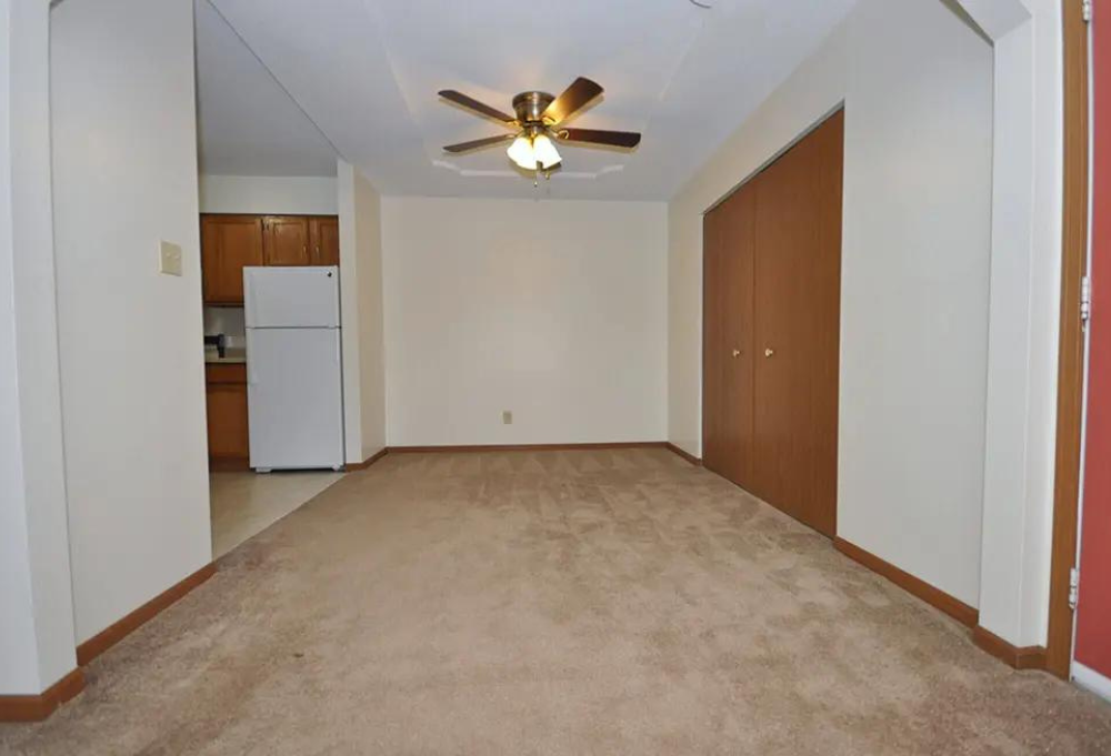 an empty living room with a ceiling fan