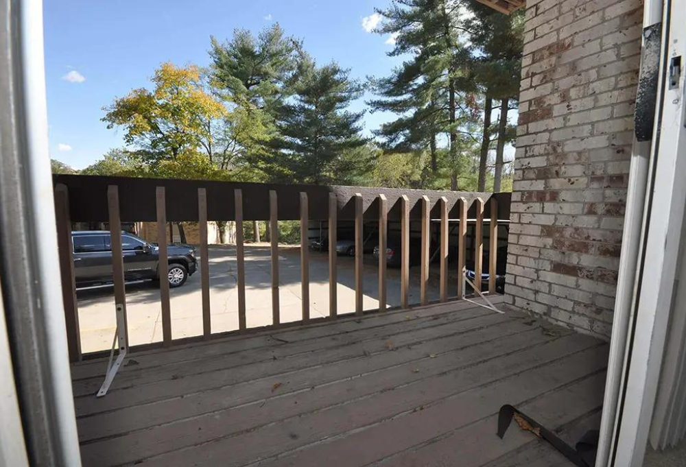 a view of a balcony with a wood railing and a brick wall
