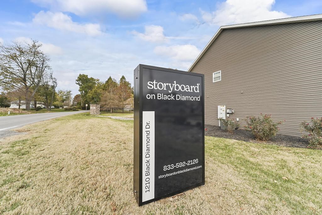 a sign in the grass in front of a building