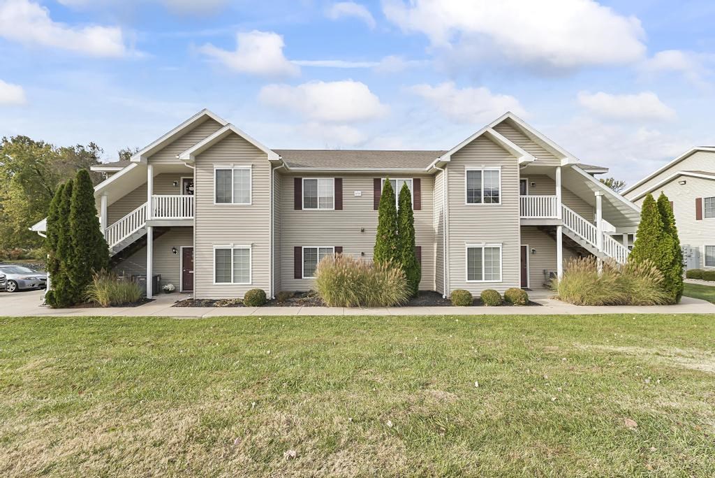 a large apartment building with a lawn and a car parked in front