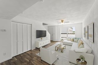 a living room with a white couch and a tv on the wall