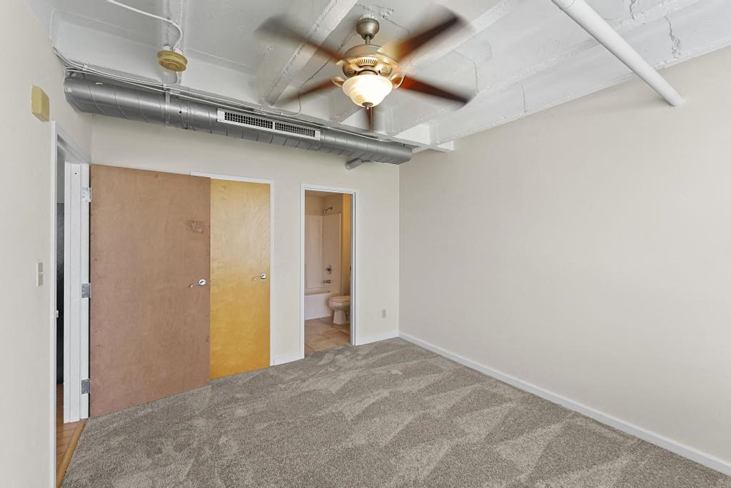 a room with a ceiling fan and a door to a bathroom