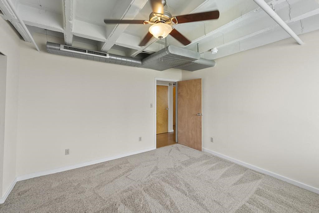a bedroom with white walls and a ceiling fan