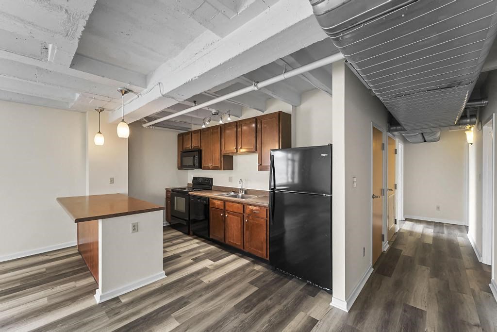 a kitchen with a black refrigerator freezer next to a stove top oven