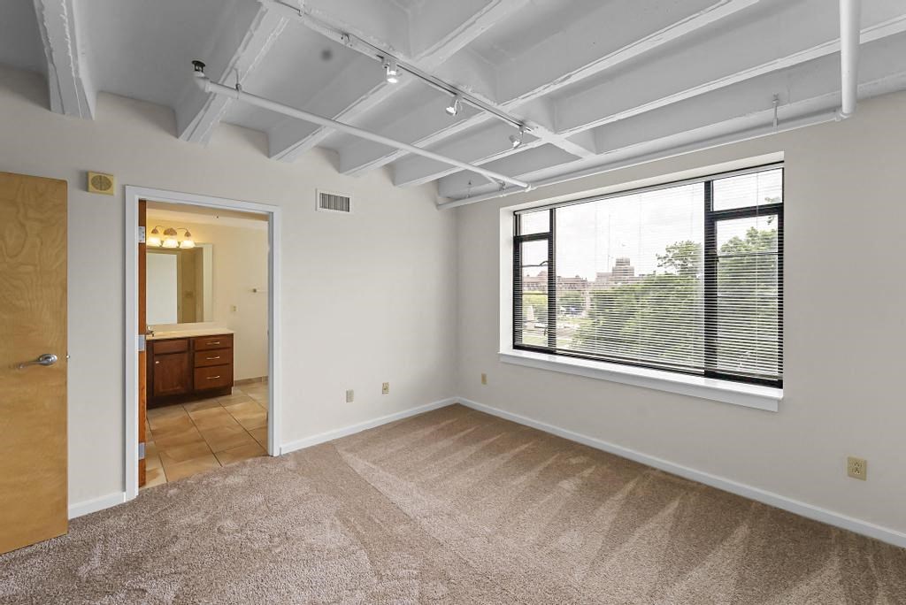 a bedroom with a large window and a door to a bathroom