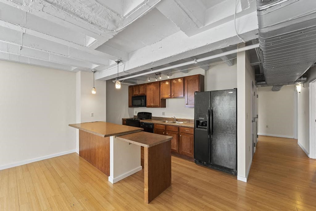 a kitchen with a black refrigerator freezer next to a stove top oven