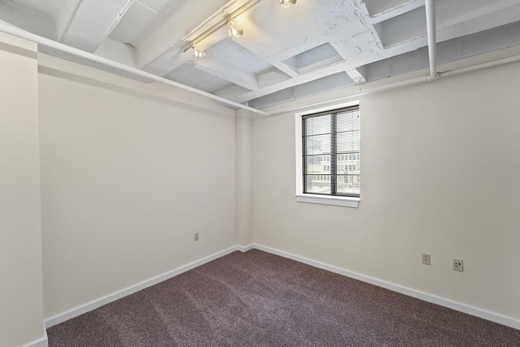 a bedroom with white walls and a window