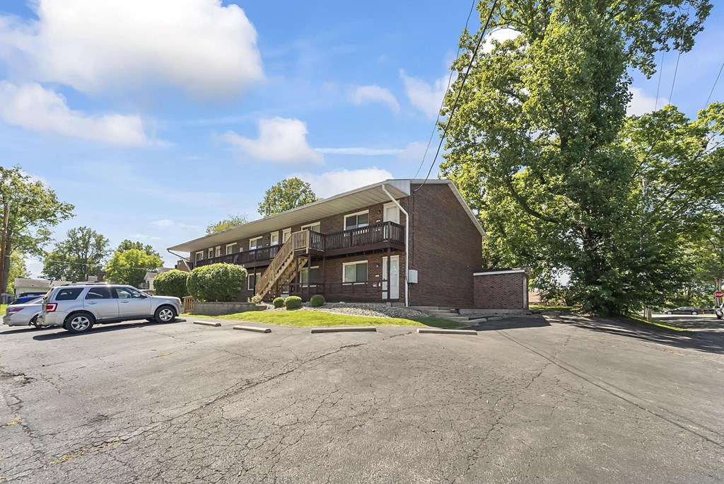 a brick apartment building with a parking lot in front of it