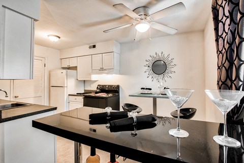 A modern kitchen with a black countertop and a ceiling fan.