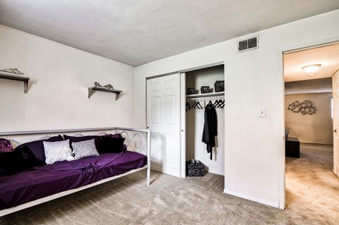 A bedroom with a purple bed and a white door.