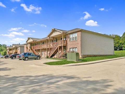 a row of apartment buildings with cars parked outside